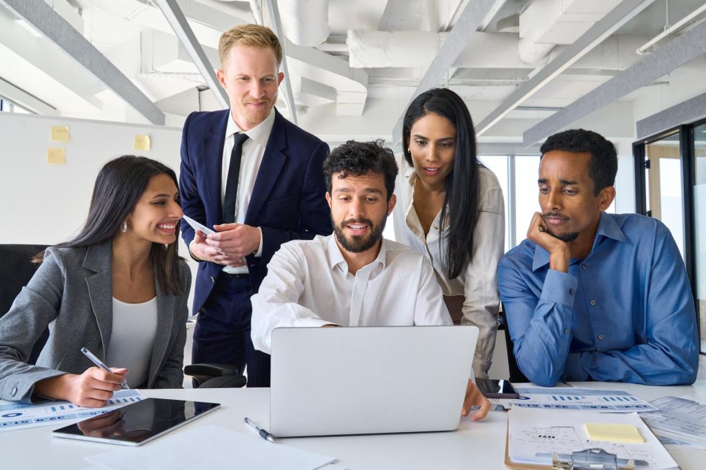 Group of professionals gathered together working on laptop